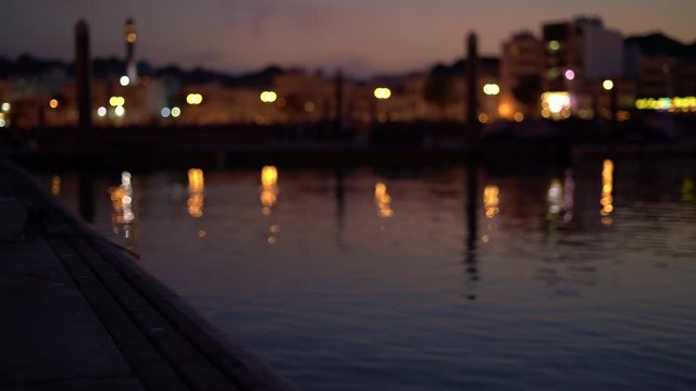 dock with water ripples reflection of lights and city in Muttrah, Oman