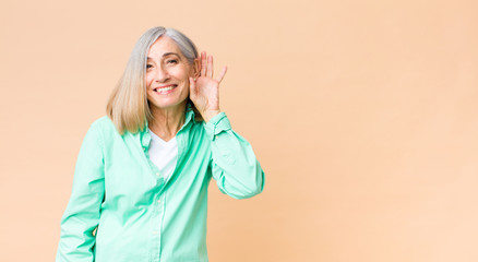 middle age cool woman smiling, looking curiously to the side, trying to listen to gossip or...