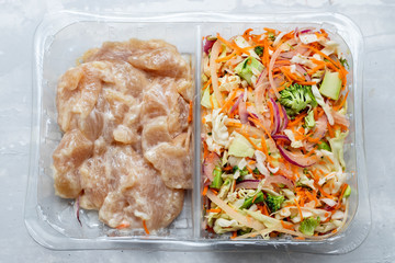 preparation for chicken with vegetables in plastic box on ceramic background