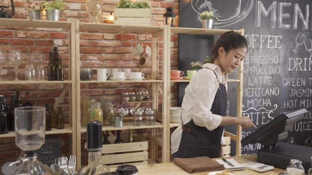 smiling woman barista in apron making coffee pour into cup put on wood plate. young girl bartender preparing drink and crossiant for customer in counter. preparation service lifestyle concept.