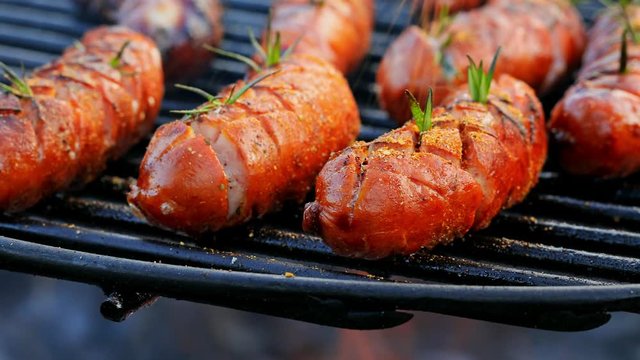 Closeup of tasty sausage on grill with spices and herbs