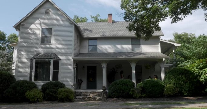 Establishing Shot Of A Two Story Grey House With Wood Siding In The Summer