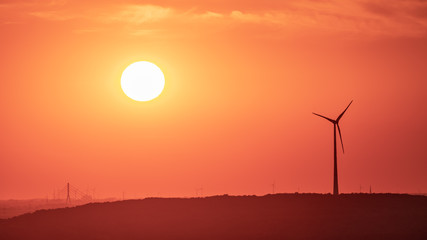 The setting sun and some wind turbines in the Ruhr Area, seen from the Halde Haniel, Bottrop, North...
