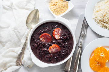 typical brazilian food black beans with smoked sausages in white bowl