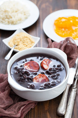 typical brazilian food black beans with smoked sausages in white bowl