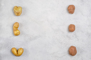 Despicable potatoes of different shapes on a gray background, copy space