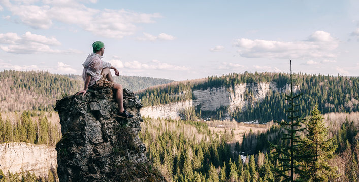 Young hiker sitting and relaxing on top of a mountain