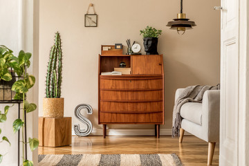 Stylish and vintage interior design of open space with wooden retro cabinet, design sofa, pendant...