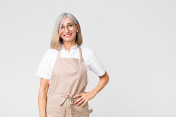 middle age baker woman smiling happily with a hand on hip and confident, positive, proud and...