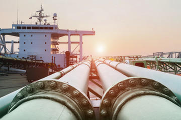 Steel long pipe connect in crude oil factory, On deck of chemical tanker ship with pipe line connection while the ship on acccomomodation deck background and sunset