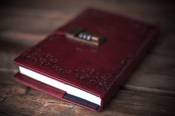Rotes Tagebuch mit unscharfem Hintergrund auf einem braunen Holztisch.