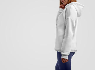 Mockup clothes series. Young caucasian girl in a blank hoodie and blue pants isolated on the white studio backgrounds.