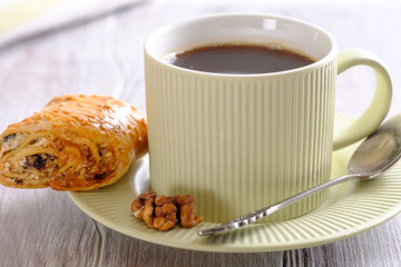 Fresh and rouge rolls with nuts, raisins and meringues on a wooden table and a cup with aromatic coffee