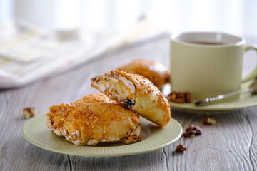 Fresh and rouge rolls with nuts, raisins and meringues on a wooden table and a cup with aromatic coffee
