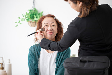 美容部員にメイクされる中高年女性（チーク・ファンデ）