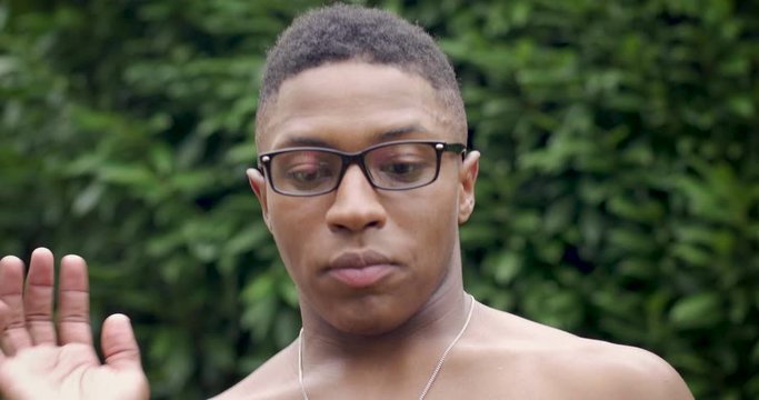 Portrait of a young black man swatting at a bug that is annoying him