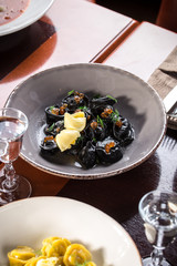Traditional Italian black ravioli with fish roe and butter and vodka shot on wooden table at restaurant