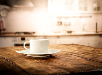 Table background in kitchen interior and woman hands with cup of coffee 