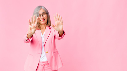 middle age cool woman smiling and looking friendly, showing number nine or ninth with hand forward,...