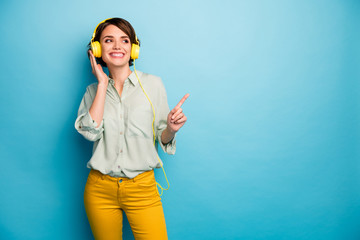 Photo of cheerful lady listen radio stylish earphones raise finger indicating empty space wear...