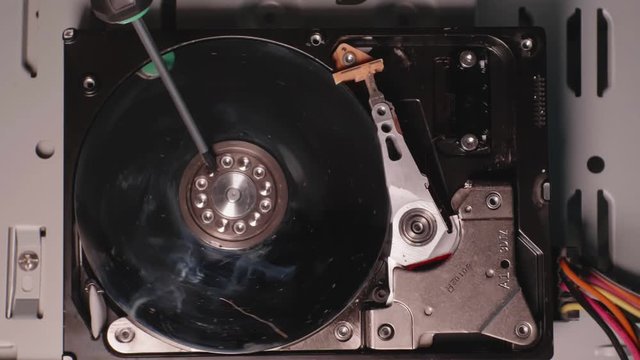 Screwdriver spins plate of open hard drive and try to scratch disk. Slowmo macro