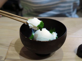 A bowl of fresh milk ice cream flavored over green tea or Japanese matcha on wooden tray.