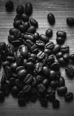 Black roasted coffee beans are on wooden desk,