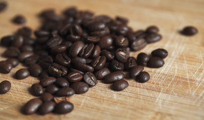 Roasted coffee beans are on wooden desk, close-up