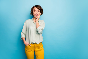 Photo of funny beautiful lady short hairdo look open mouth read discount banner advert arm on chin wear casual green shirt yellow trousers isolated blue color background