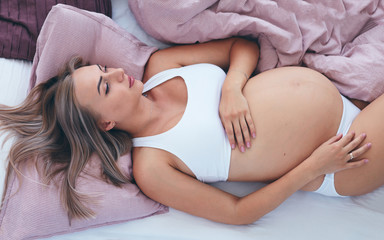 young pregnant woman relaxing in bed in the morning - obrazy, fototapety, plakaty