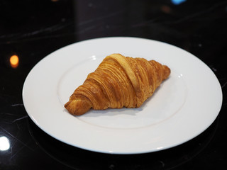 A crispy baked croissant isolated on white plate. Breakfast concept.