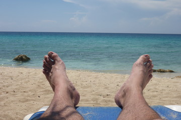 View of feet on a beach with clear blue ocean on a vacation