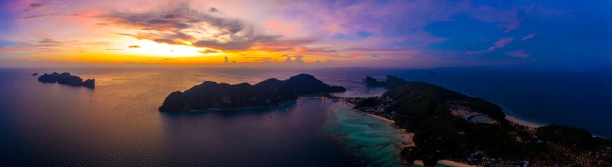 Fototapeta na wymiar Aerial view of Phi Phi, Maya beach with blue turquoise seawater, mountain hills, and tropical green forest trees at sunset with Andaman sea in Phuket island in summer, Thailand in travel trip. Nature.