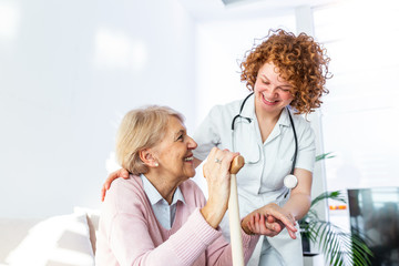 Friendly relationship between smiling caregiver in uniform and happy elderly woman. Supportive...