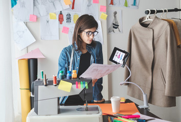 Young female fashion designer using modern technology on work