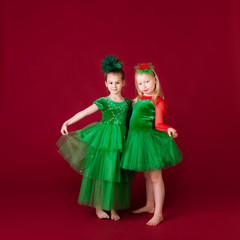 Beautiful little girl princesses dancing in luxury green dress isolated on red background. Carnival party with costumes