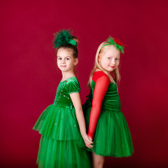 Beautiful little girl princesses dancing in luxury green dress isolated on red background. Carnival party with costumes