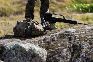 Soldier on top of a rock with a backpack and the gun