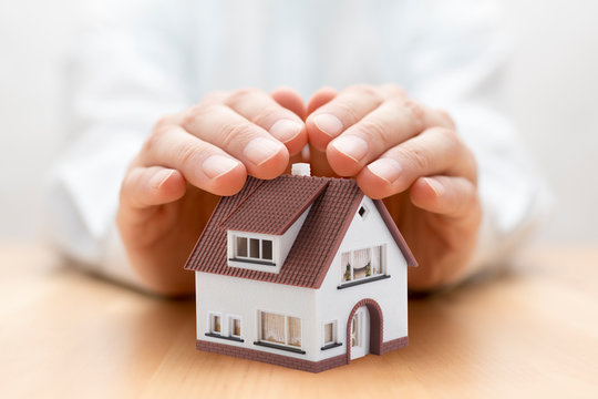 Property insurance. House miniature covered by hands