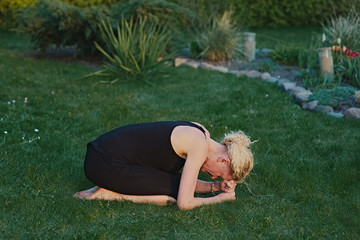 Young woman doing yoga in meditation posture on a mat in the garden.