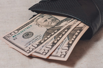 Black wallet with dollars 50 on a gray background.