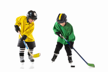 Fototapeta premium Little hockey players with the sticks on ice court and white studio background. Sportsboys wearing equipment and helmet practicing. Concept of sport, healthy lifestyle, motion, movement, action.