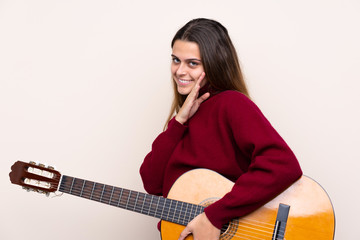 Teenager girl with guitar over isolated background whispering something