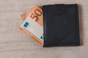 Euro banknotes and black wallet on gray background