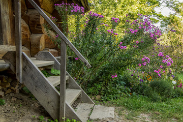 wood material rustic porch exterior village house stairs near flower bed garden foliage nature