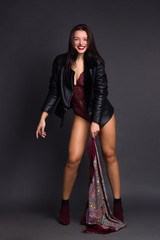 a brunette girl in Burgundy bodysuit poses and dances on a gray Studio background