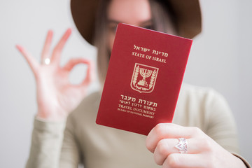 Woman with Israel travel document passport on white background girl making OK sign. immigration, travel concept