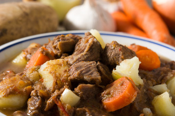 Irish beef stew with carrots and potatoes on wooden table.Close up