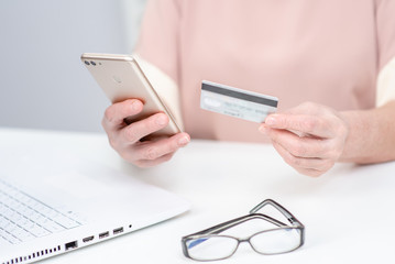 Senior woman checks her finance on credit card with smartphone
