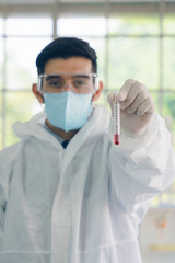Fototapeta na wymiar coronavirus covid-19 infected blood sample in sample tube in hand of scientist with biohazard protection clothing in laboratory